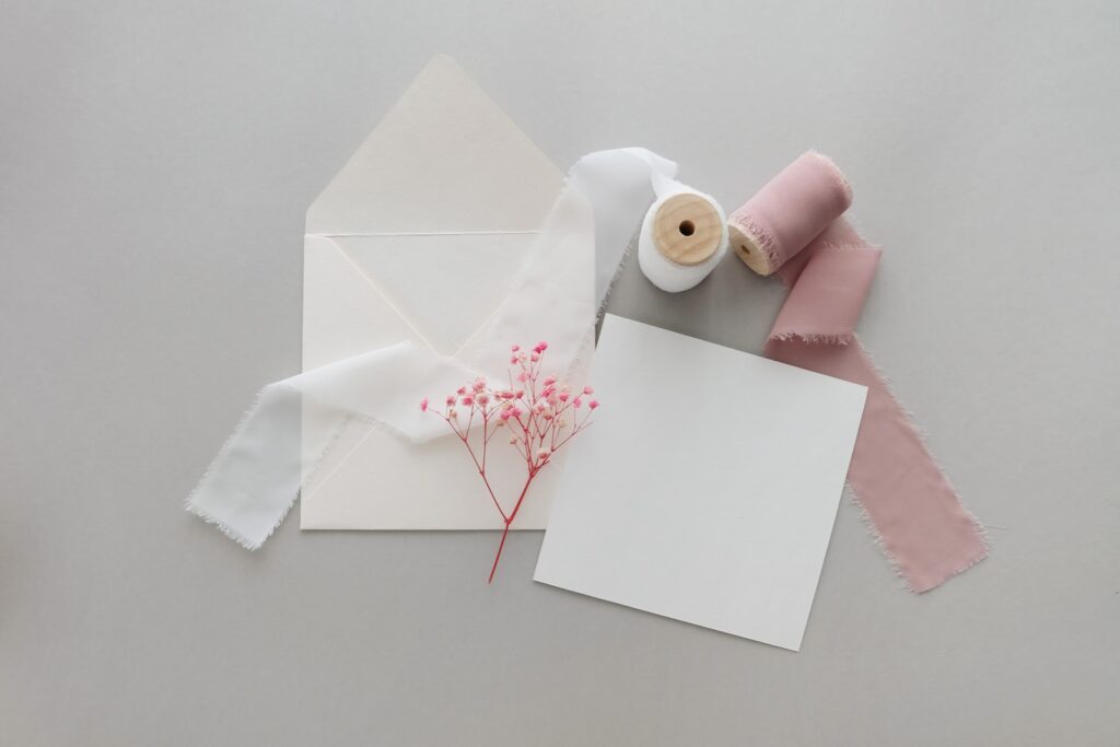 a white envelope with a pink flower and a pair of scissors next to it