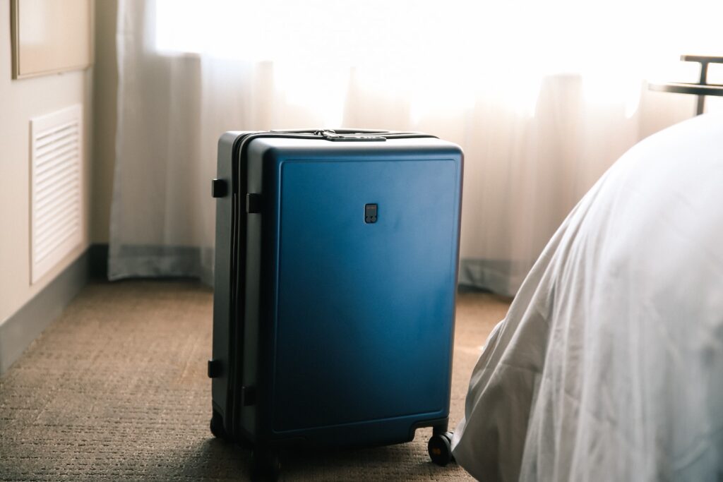 a blue suitcase sitting on the floor next to a bed