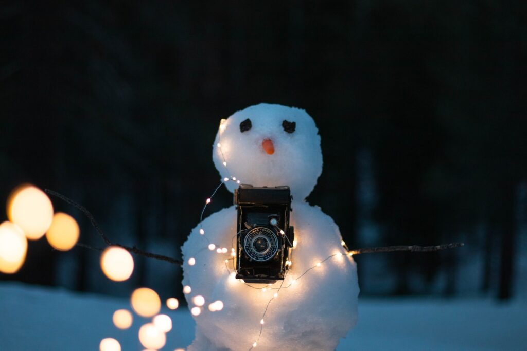 snowman with lighted string lights and black DSLR camera