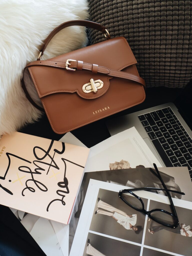 brown leather handbag beside macbook pro