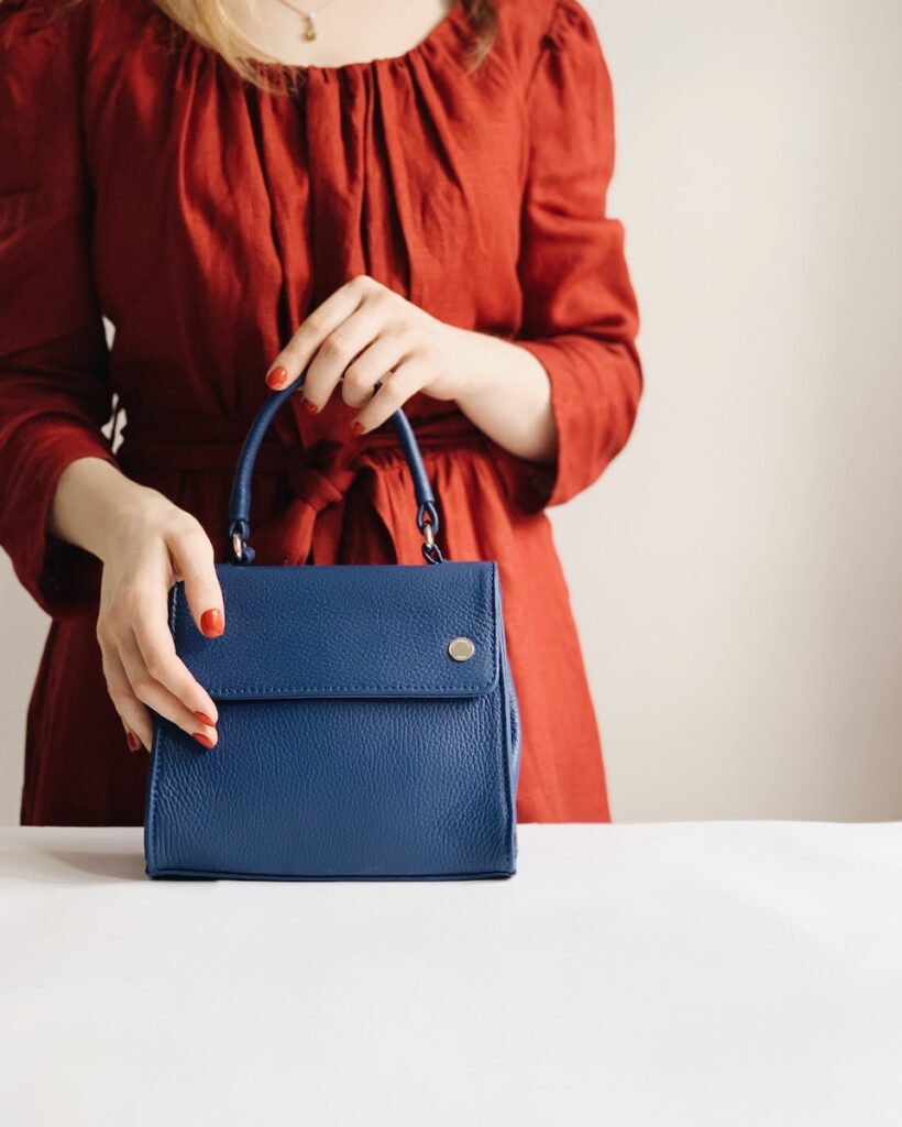 woman holding blue leather handbag