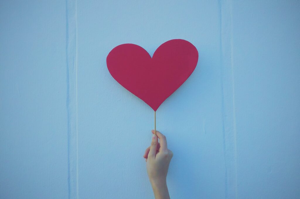 person holding heart shaped red balloon